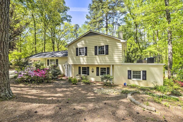 A two-story house with a front porch, surrounded by trees and a garden.