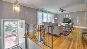 Un vaste espace de vie comprenant un canapé gris, une table à manger et un escalier agrémenté d’une rampe décorative.