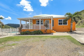 A two-story house with a white porch and a swimming pool in the background. - Breezy St. Croix Bungalow w/ Pool & Ocean Views! (Christiansted)