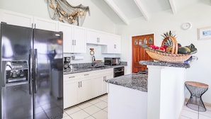 Una cocina moderna con armarios blancos, un refrigerador de acero inoxidable, un microondas y una cafetera.