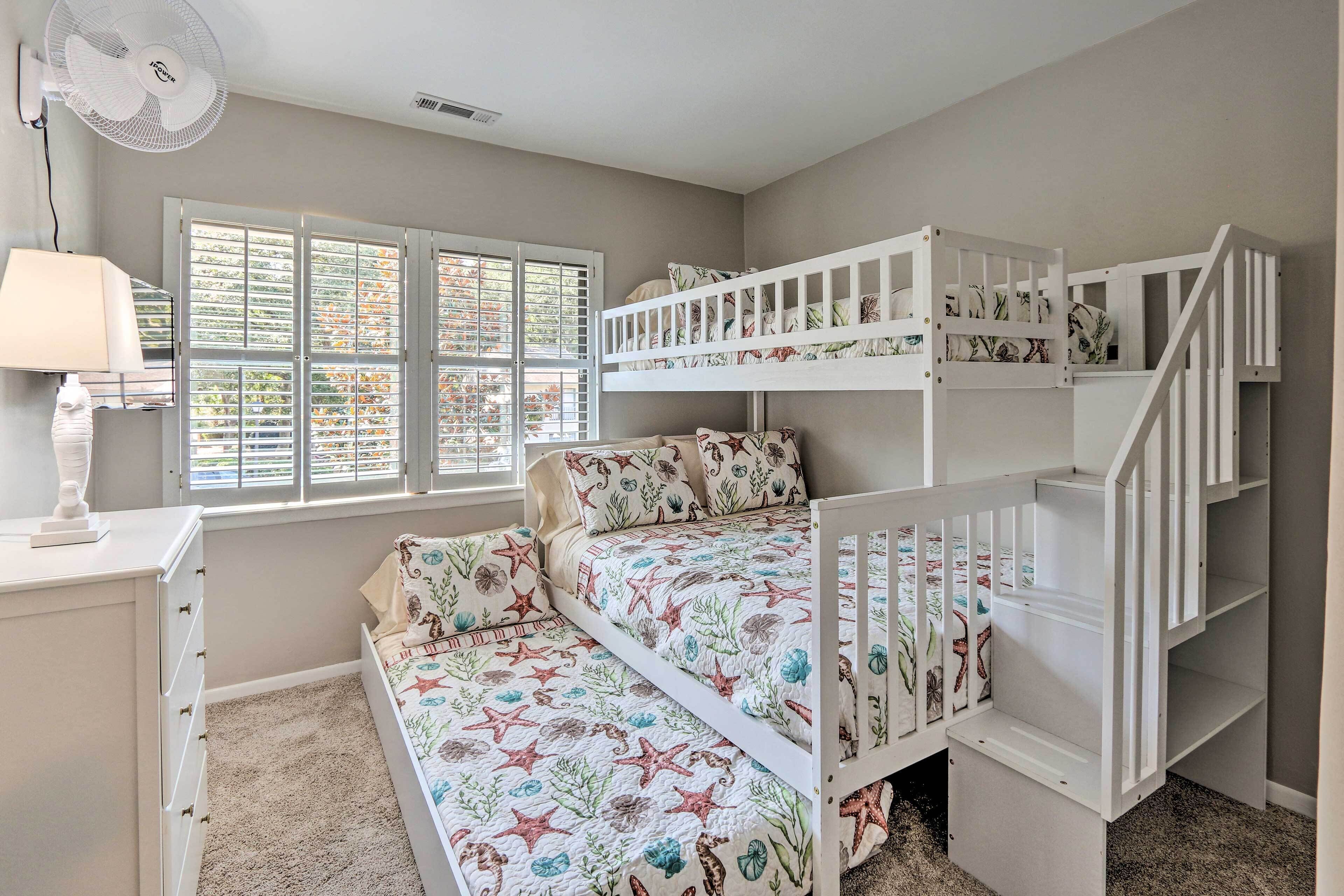 A child's bedroom with bunk beds, a desk with a lamp, and a window with blinds.