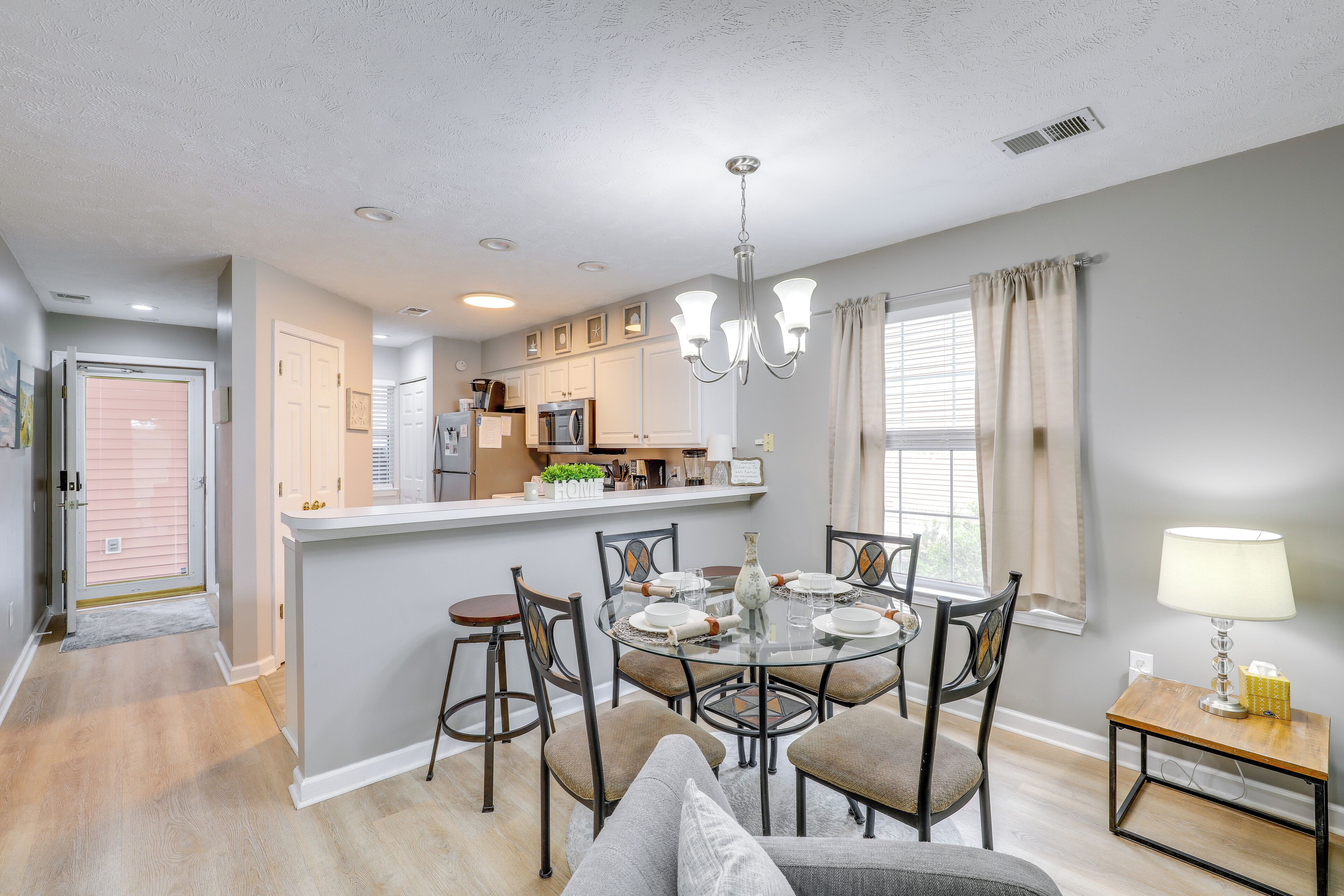 A modern kitchen with white cabinets, a central island, and a dining area with a round table and chairs.