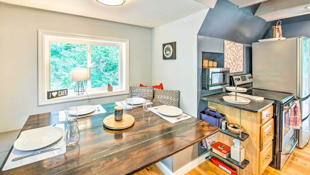Una cocina moderna con horno empotrado, refrigerador y comedor con una mesa de madera para dos personas.
