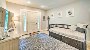 Un dormitorio con una cama, un escritorio con lámpara y una puerta con paneles de vidrio emplomado.