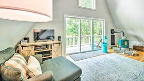 Una sala de estar acogedora con un televisor grande, un mueble de madera para equipos electrónicos y una chimenea de piedra.