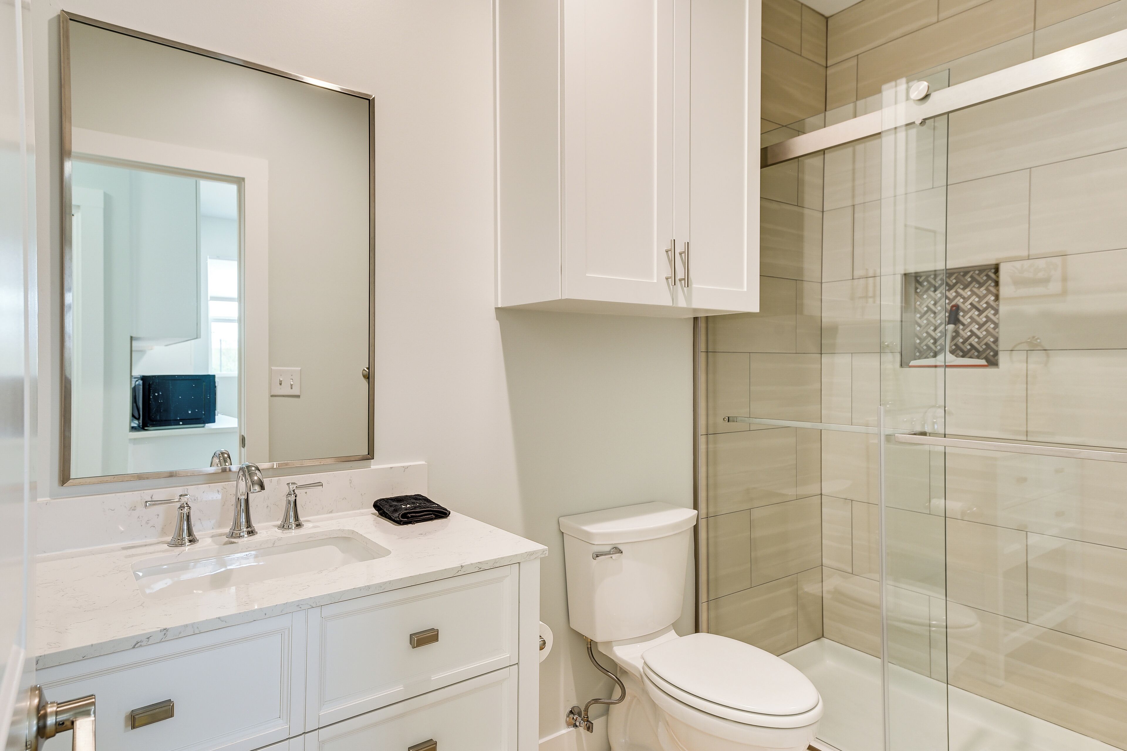 A modern bathroom with a white sink, mirror, and toilet.