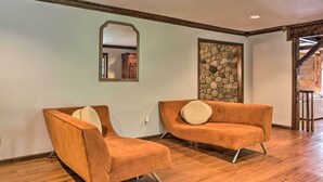 A room with two orange armchairs, a stone accent wall, and a wooden floor.