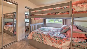 Une chambre avec un lit superposé, une couvre-lit à motifs, un miroir et une fenêtre donnant sur l’extérieur.