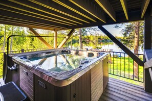 A hot tub on a wooden deck with a view of a lake and trees. - Hot Tub & Mtn Views: Waterfront Grand Lake Cabin! (Grand Lake)