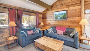 A cozy room with wooden walls, two sofas with patterned cushions, a wooden coffee table, and two lamps. - Hot Tub & Mtn Views: Waterfront Grand Lake Cabin! (Grand Lake)