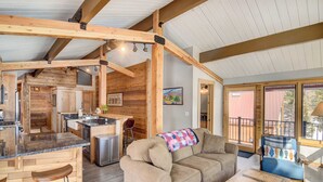 A spacious living area with a sofa, a coffee table, and a kitchen area with a bar. - Hot Tub & Mtn Views: Waterfront Grand Lake Cabin! (Grand Lake)