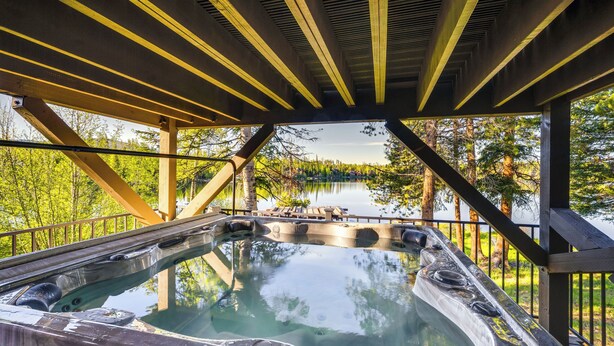 A hot tub under a wooden deck with a view of a lake and trees. - Hot Tub & Mtn Views: Waterfront Grand Lake Cabin! (Grand Lake)