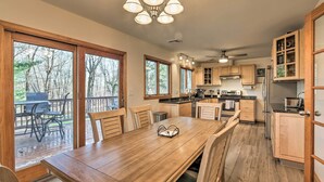 A spacious kitchen with wooden cabinets, a dining table, and large windows overlooking a deck. - Family-friendly Woodbury Home With Yard + Deck! (Woodbury)