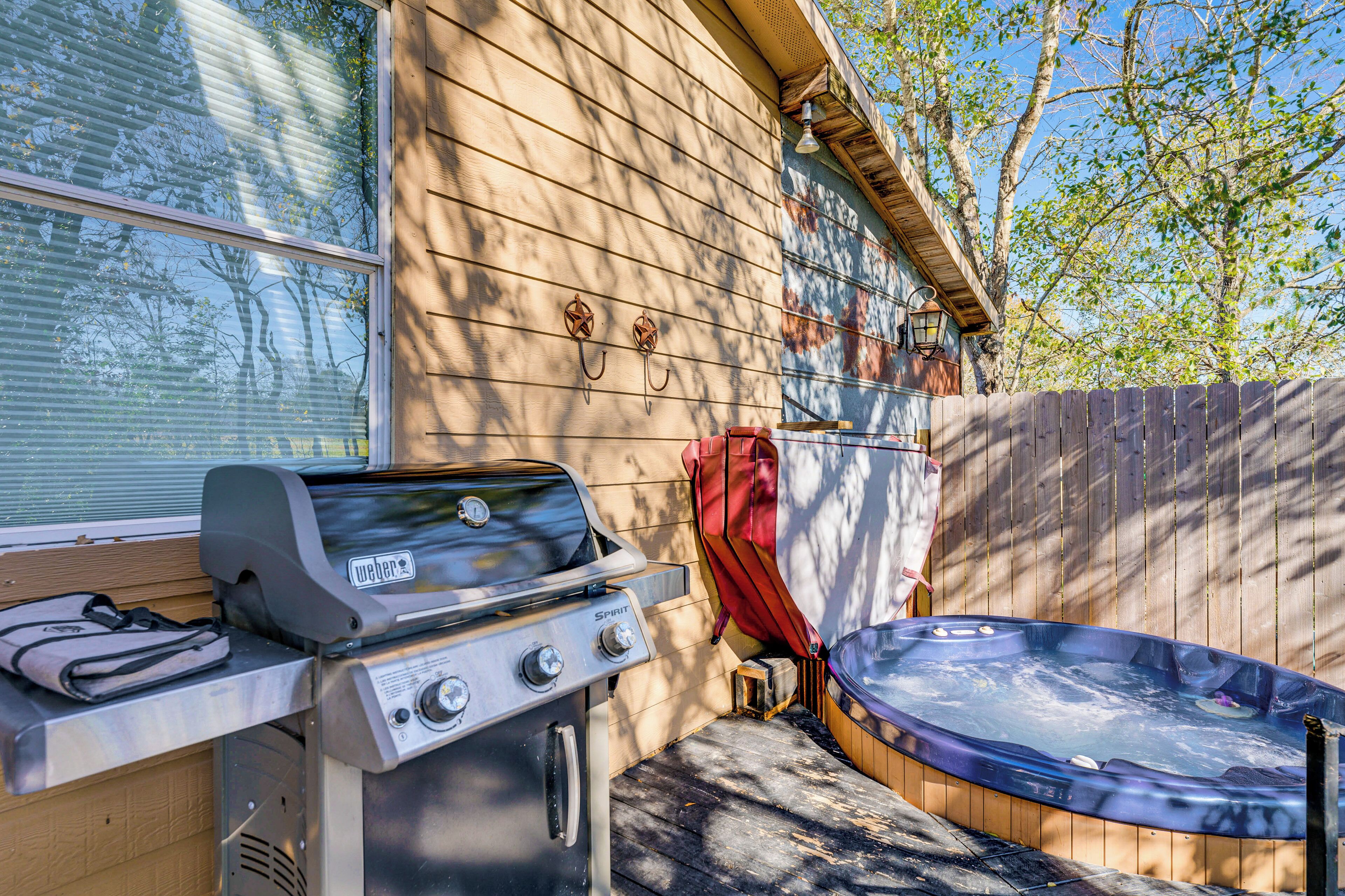 A backyard with a grill, a hot tub, and a wooden fence.