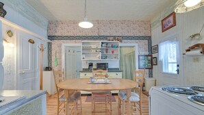 A kitchen with a wooden dining table, chairs, and a white stove. - Historic Houghton Lake Getaway Near Shoreline (Houghton Lake)