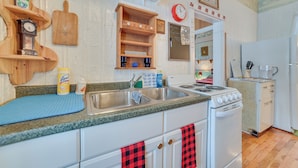 A kitchen with a sink, stove, and wooden shelves. - Historic Houghton Lake Getaway Near Shoreline (Houghton Lake)