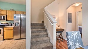 A kitchen with a stainless steel refrigerator, wooden cabinets, and a microwave. There is a staircase leading to a dining area with a table and chairs. - 9 Mi to Disney: Resort Townhome in Davenport! (Davenport)