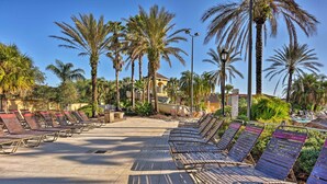 A sunlit outdoor area with rows of metal sun loungers and palm trees. - 9 Mi to Disney: Resort Townhome in Davenport! (Davenport)