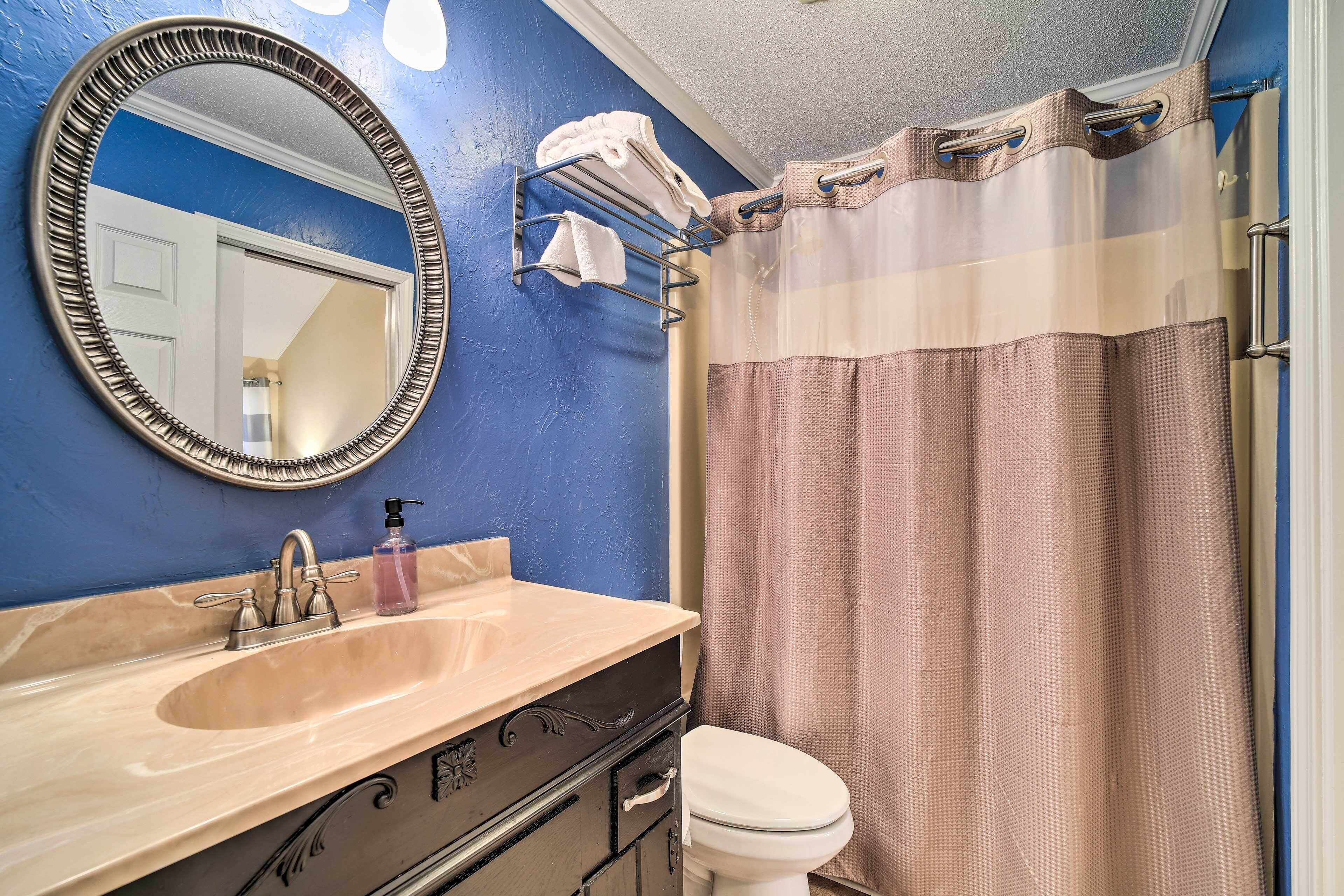 Une salle de bain avec un mur bleu, un lavabo beige, des toilettes blanches et un rideau de douche.