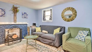 A living room with a grey sofa, a green armchair, a fireplace, and decorative wall art. - Home w/ Fire Pit - 8 Mi to Dtwn Mile Square! (Indianapolis)