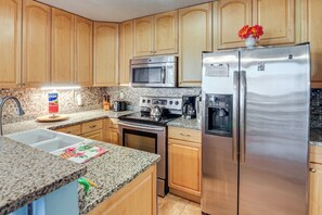 A kitchen with wooden cabinets, a stainless steel refrigerator, a microwave, a stove, and a sink. - < 1 Mi to Beach: Condo w/ Community Perks in Hhi! (Hilton Head Island)