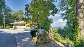 A house with a gravel driveway, a wooden deck, and a stone wall.