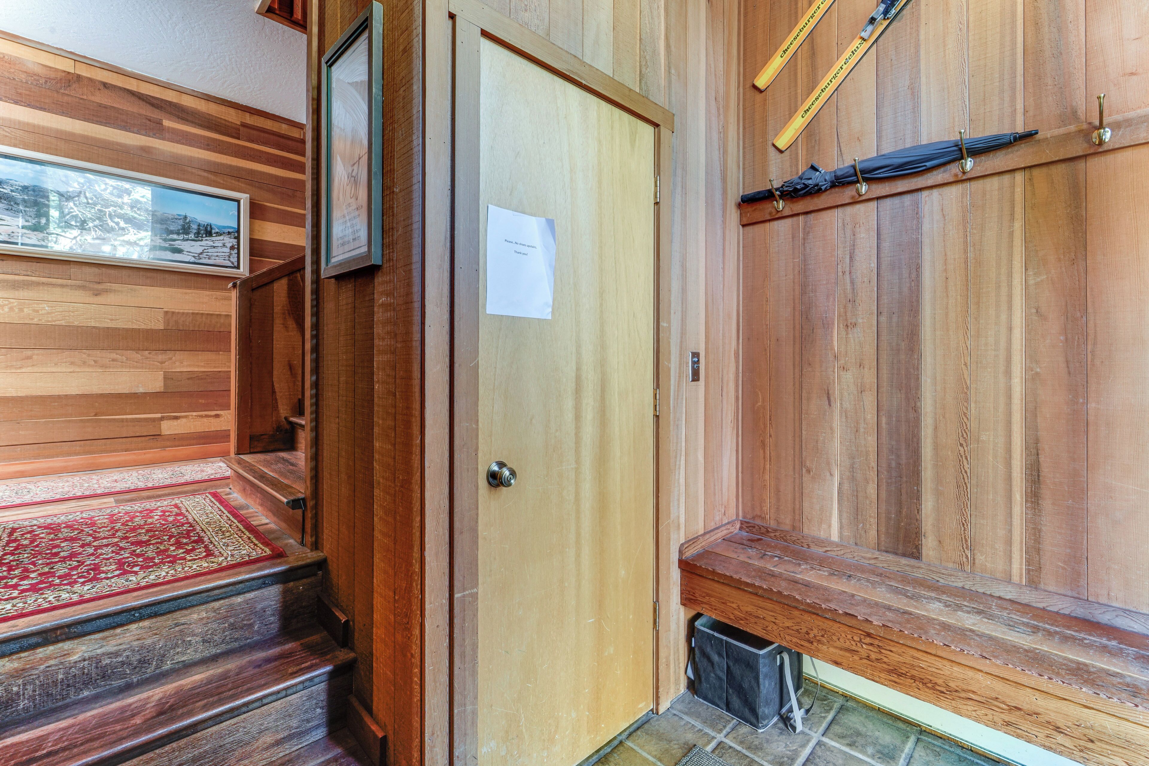 Un interior de madera con un banco, una puerta y un cuadro en la pared.