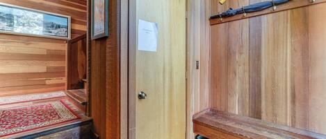 Un interior de madera con un banco, una puerta y un cuadro en la pared.