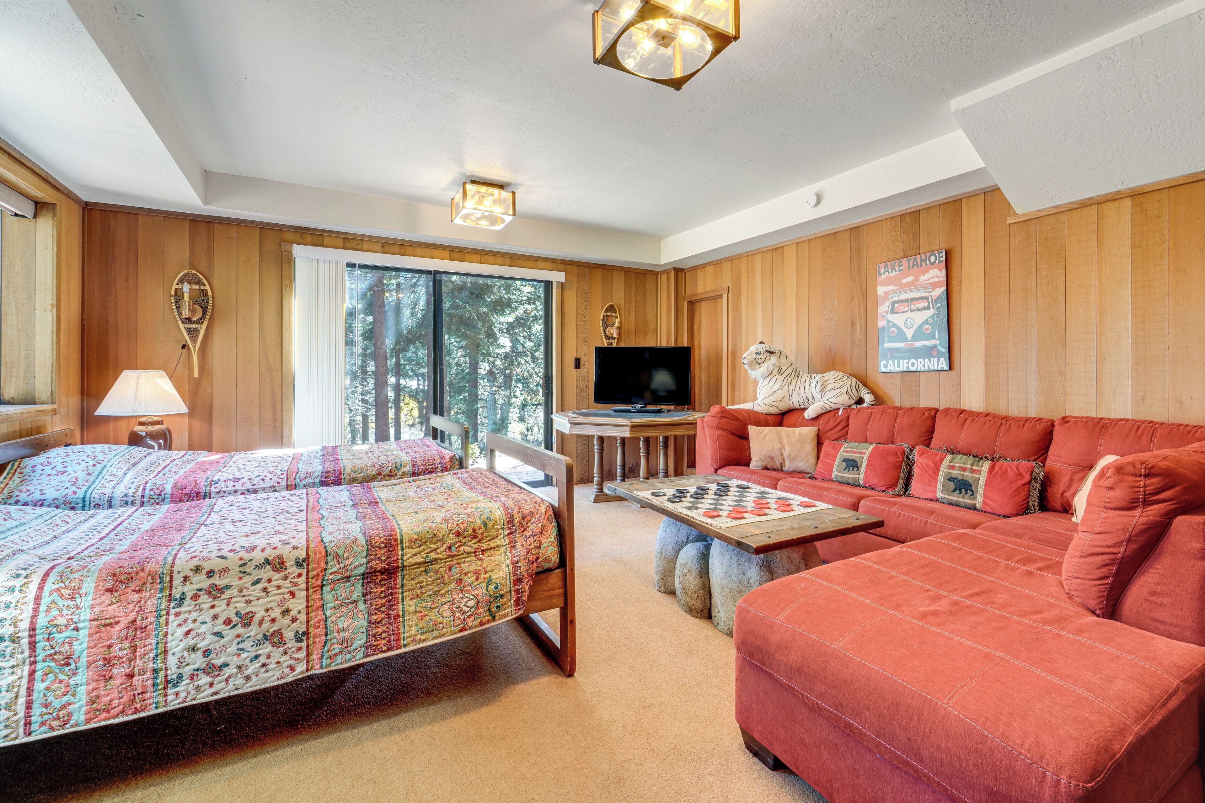 A cozy room with a bed, a sofa, a table with a chessboard, and a television.