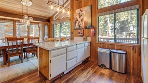 A wooden interior with a kitchen island, dining area, and large windows. - Family-friendly Truckee Cabin Near Ski Shuttle! (Truckee)