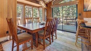 A wooden dining area with a large table and chairs, large windows, and a view of the outdoors. - Family-friendly Truckee Cabin Near Ski Shuttle! (Truckee)