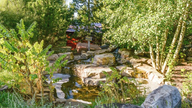 Un étang naturel entouré de rochers et de verdure, avec un panneau en bois en arrière-plan.