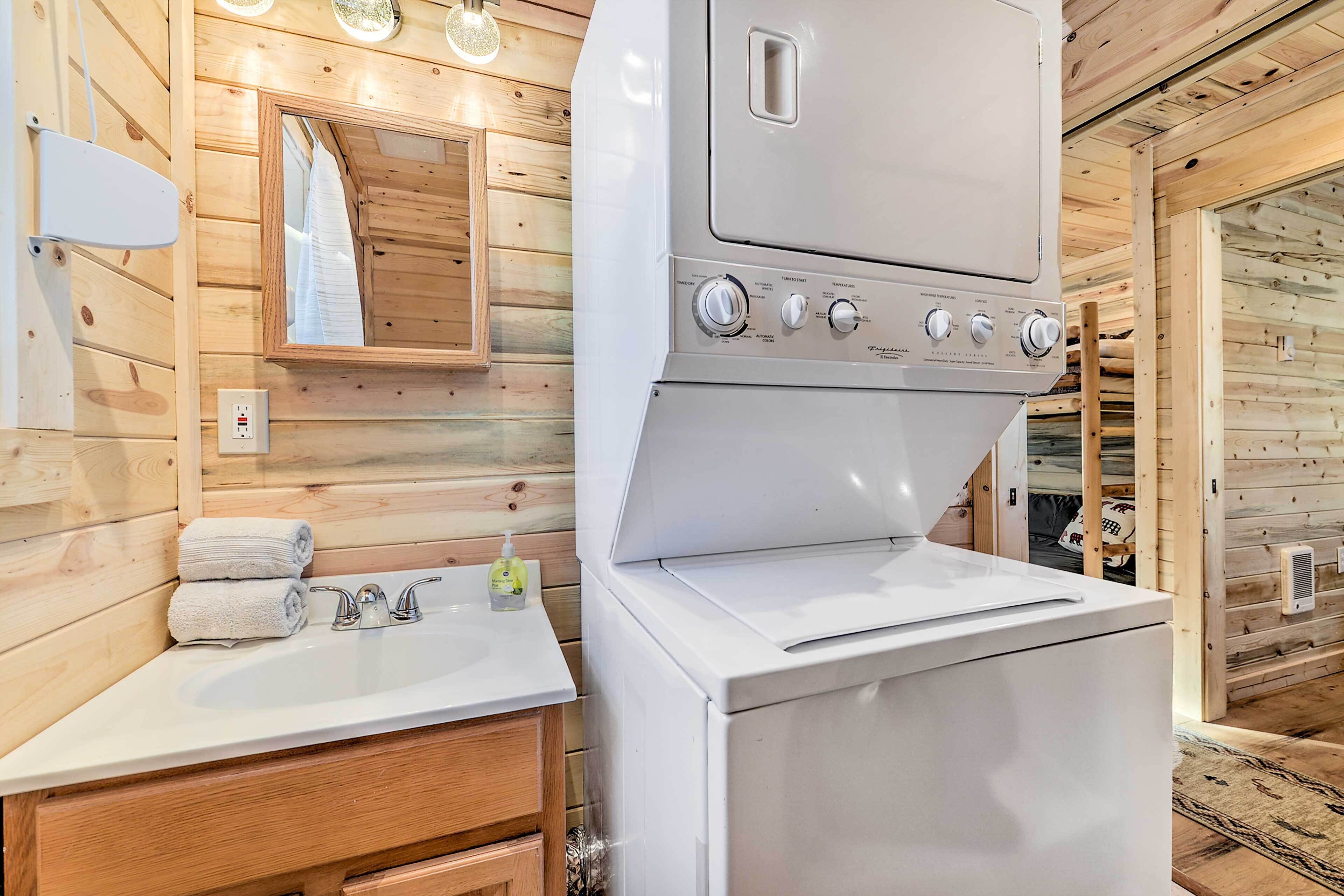 Un baño pequeño con un lavamanos blanco, tocador de madera y lavadora integrada.