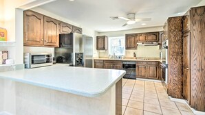 A kitchen with wooden cabinets, a large island, and modern appliances. - 20 Mi to Philly: Inviting Home w/ Yard in Wayne! (Wayne)