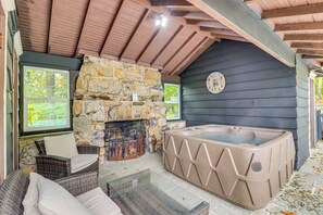 Une cheminée en pierre, un jacuzzi, des meubles en osier et une horloge au mur.