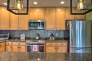 A kitchen with wooden cabinets, a stainless steel refrigerator, a microwave, a stove, and a tiled backsplash. - Wintergreen Resort Cabin: Near the Slopes! (Roseland)
