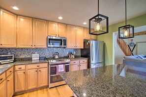 A modern kitchen with wooden cabinets, stainless steel appliances, a granite countertop, and pendant lighting. - Wintergreen Resort Cabin: Near the Slopes! (Roseland)