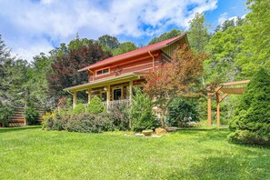 A two-story house with a red roof, surrounded by a well-maintained garden and trees. - Riverside Cabin Near West Jefferson! (Lansing)