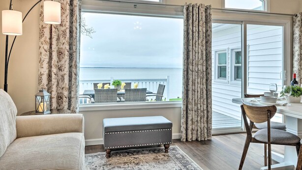 A room with a large window, a bench, a table with chairs, and a lantern on a side table. - Waterfront Cottage w/ Private Beach + Deck! (Colonial Beach)