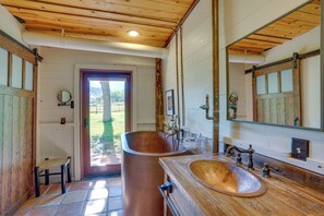 Une salle de bain avec une grande baignoire, un meuble-lavabo en bois et un miroir.