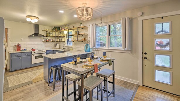 A modern kitchen with a central island, bar stools, and a chandelier. - Renovated Eureka Springs Home - 1 Mi to Downtown! (Eureka Springs)