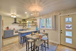 Una cocina moderna con una isla central, taburetes de bar y una araña.