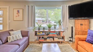 A living room with a sofa, a coffee table, a bookshelf, and a TV. - Renovated Eureka Springs Home - 1 Mi to Downtown! (Eureka Springs)