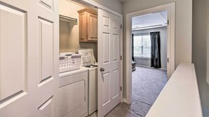 A laundry room with a washing machine, dryer, and wooden cabinets.