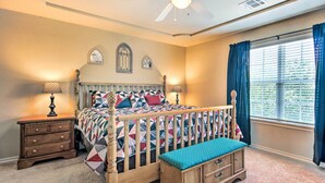 A bedroom with a wooden bed, a nightstand, a bench, and a window with curtains.