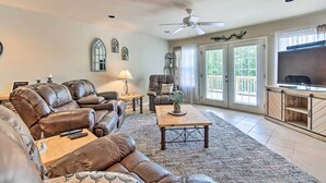 A living room with leather sofas, a wooden coffee table, a ceiling fan, and a television on a wooden cabinet.