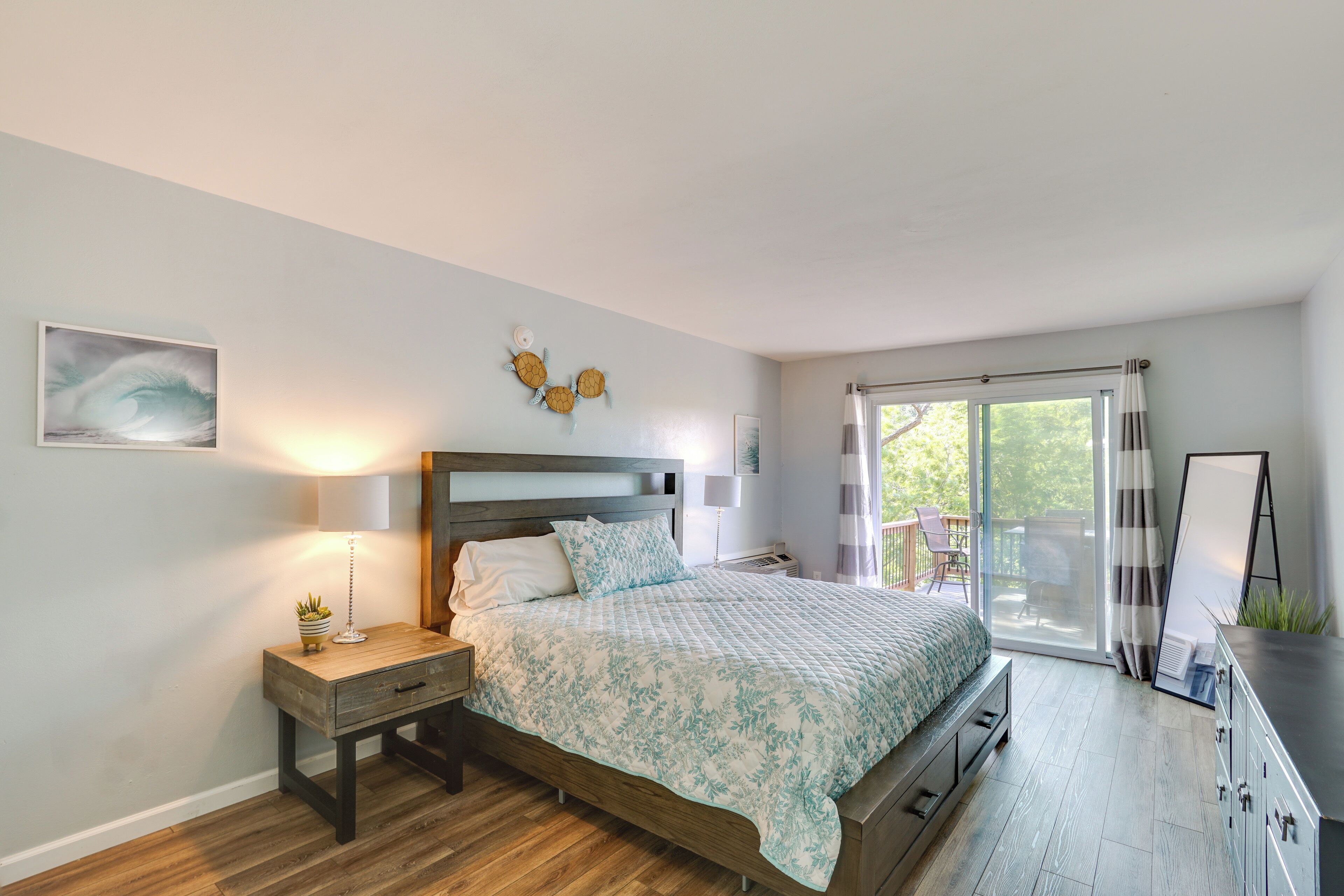 Quarto com cama, mesa de cabeceira, luminária e vista para o exterior.