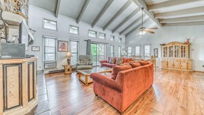 Un salon spacieux doté de planchers en bois, d’un canapé rouge, d’une armoire en bois et d’un ventilateur de plafond.