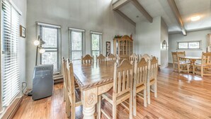 Un vaste espace dédié à la salle à manger, avec une grande table et des chaises en bois, un meuble encastré et un ventilateur de plafond.