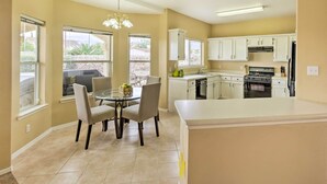 A kitchen with white cabinets, a dining table with chairs, and a large island.
